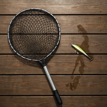 Пустой подсак лежит на деревянном настиле пирса рядом с мокрым следом приманки