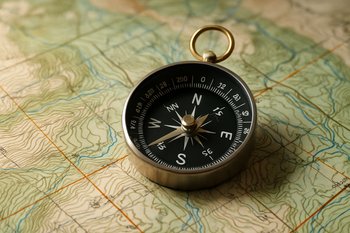 Компас лежит на разложенной карте маршрута, рядом видны небольшие пометки карандашом